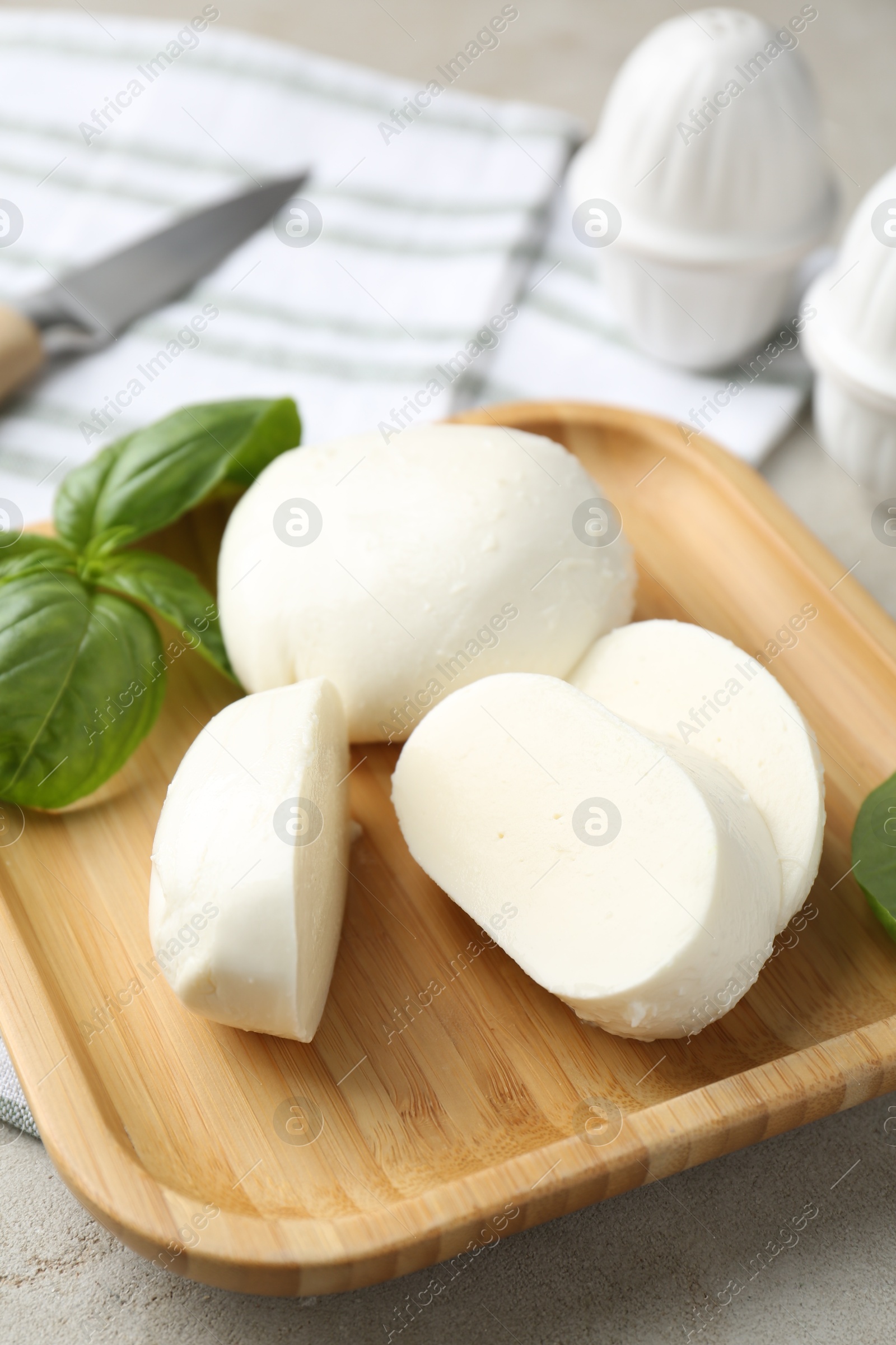 Pieces of delicious mozzarella cheese and basil leaves on grey textured table, closeup Photo of Pieces of delicious mozzarella cheese and basil leaves on grey textured table, closeup