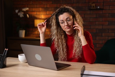 Photo of Woman talking by smartphone at desk with laptop in home office