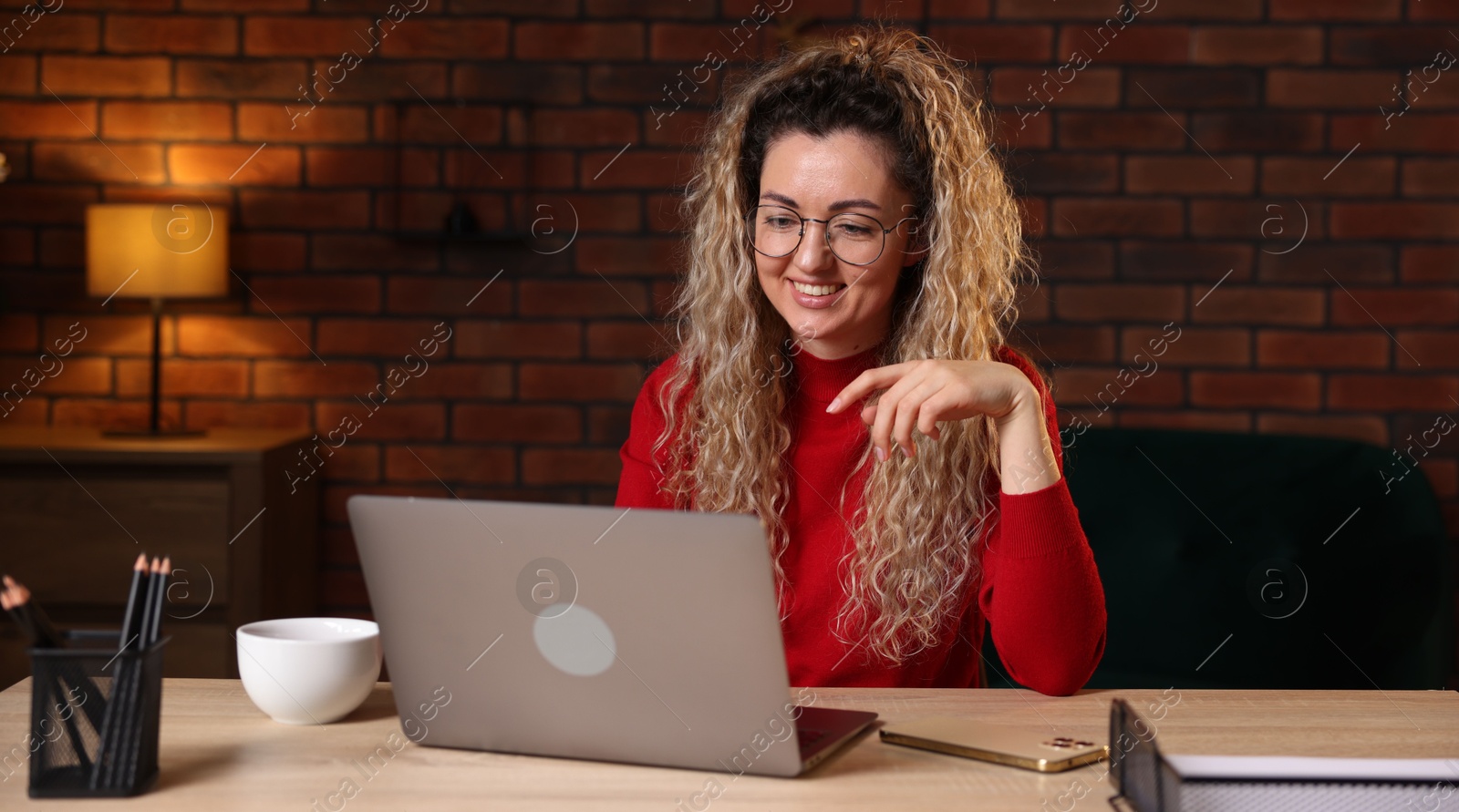 Smiling woman working with laptop at desk in home office Photo of Smiling woman working with laptop at desk in home office