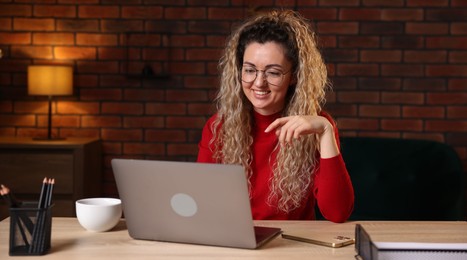 Photo of Smiling woman working with laptop at desk in home office