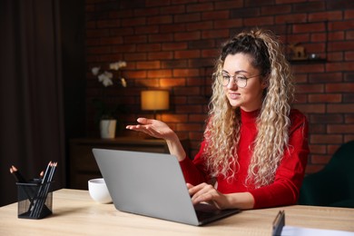 Photo of Smiling woman having videochat by laptop at desk in home office