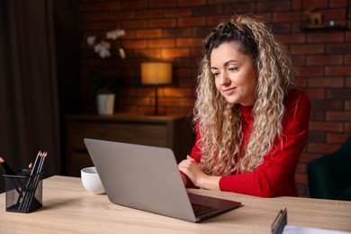 Photo of Woman working with laptop at desk in home office