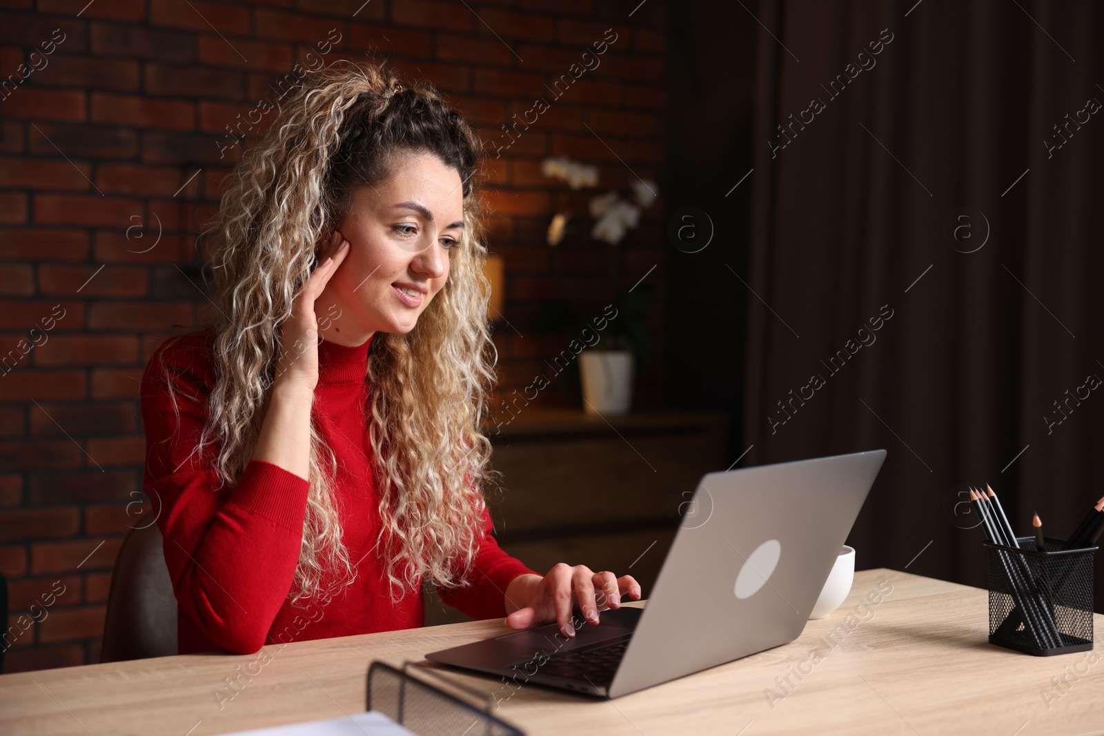 Smiling woman working with laptop at desk in home office Photo of Smiling woman working with laptop at desk in home office