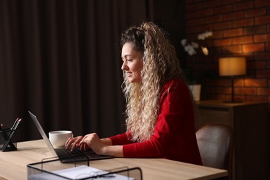 Photo of Smiling woman working with laptop at desk in home office