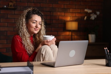 Photo of Woman working with laptop at desk in home office