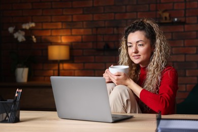 Photo of Woman working with laptop at desk in home office
