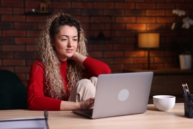 Photo of Woman working with laptop at desk in home office
