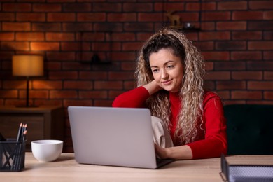 Photo of Woman working with laptop at desk in home office
