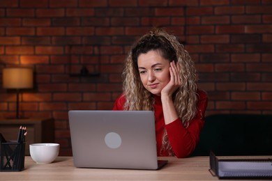 Photo of Woman working with laptop at desk in home office