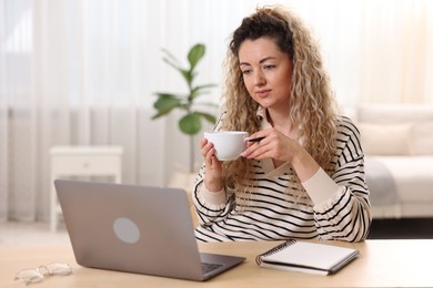 Photo of Woman working with laptop at desk in home office