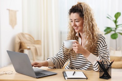 Photo of Smiling woman working with laptop at desk in home office