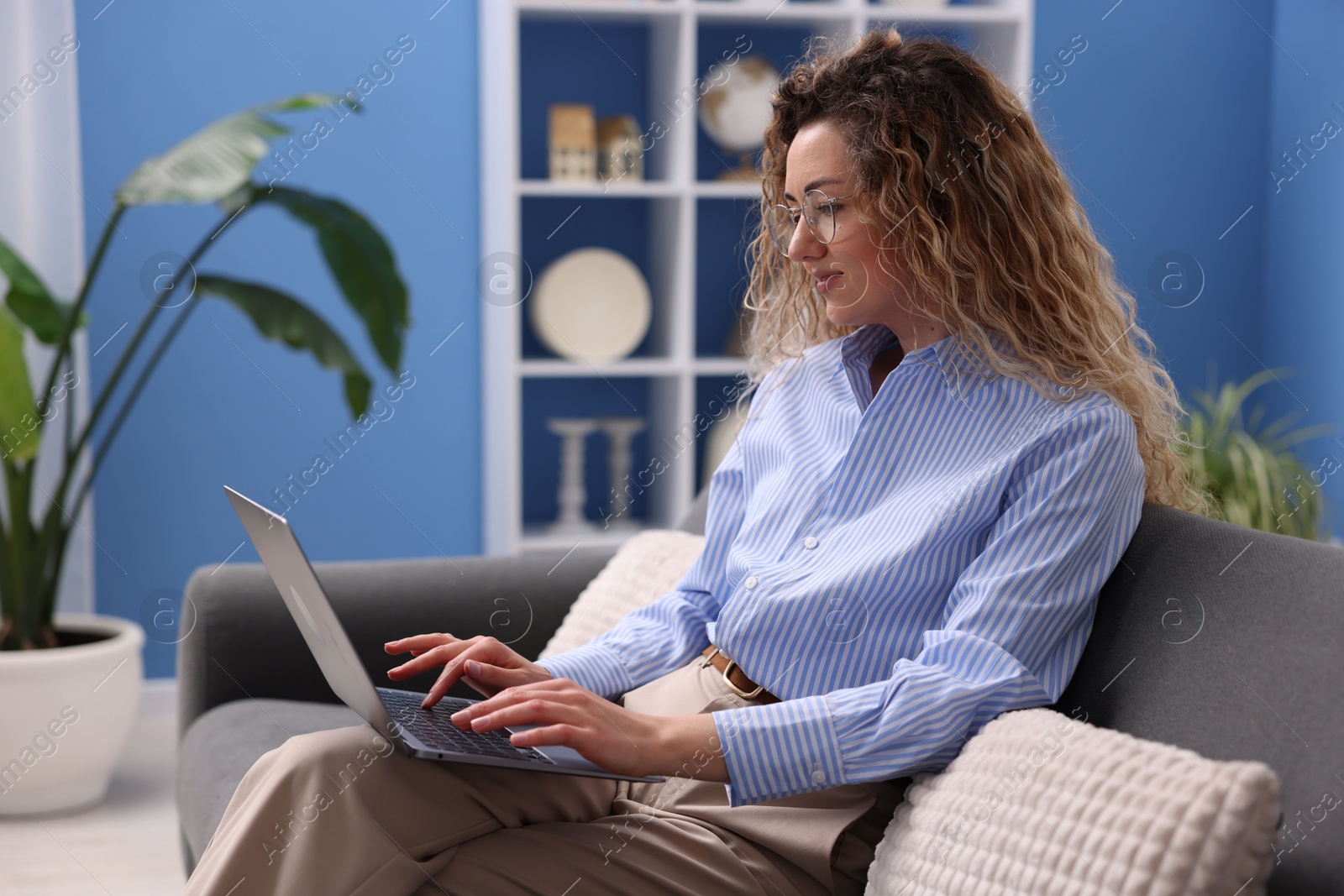 Woman working with laptop on sofa in home office Photo of Woman working with laptop on sofa in home office