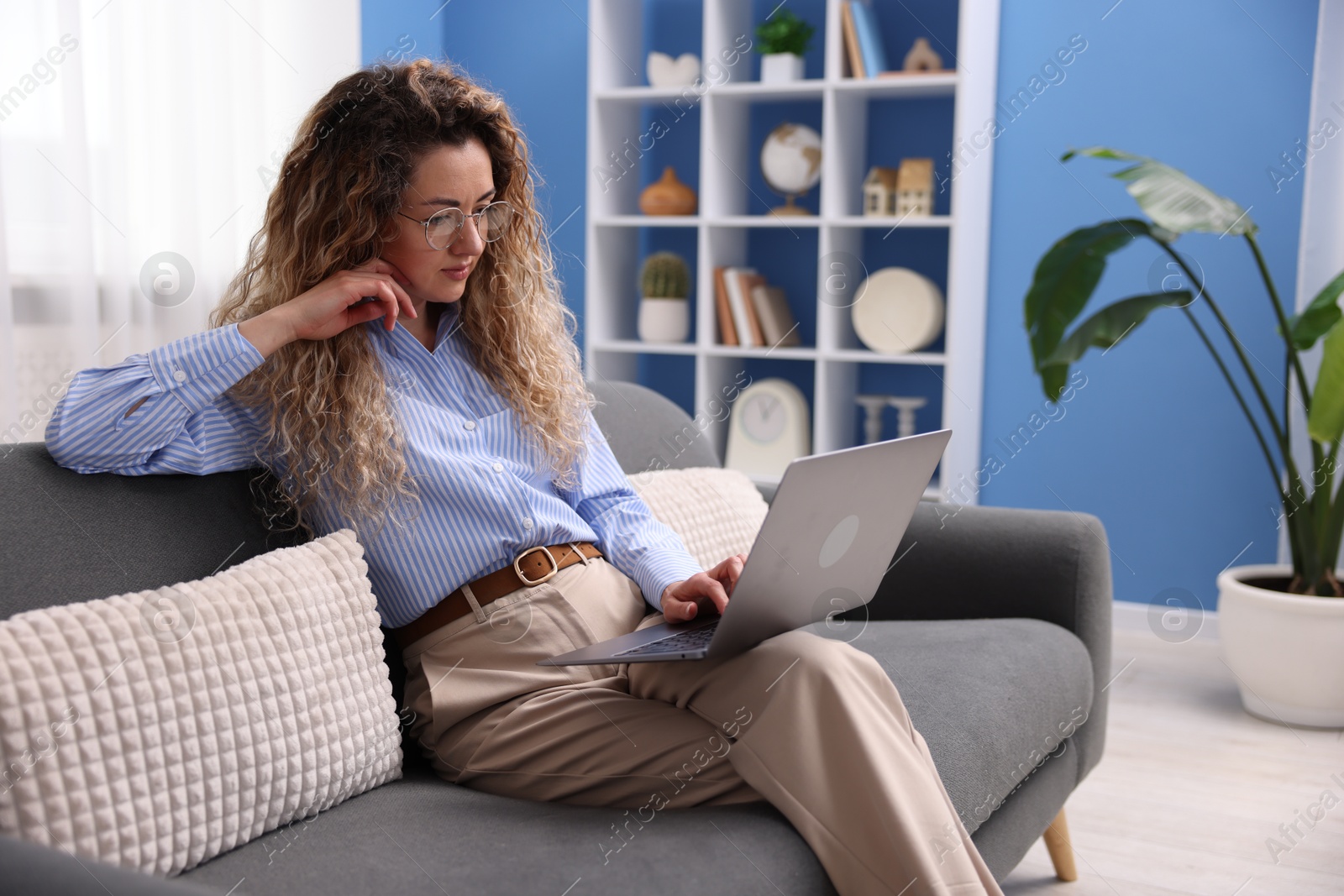 Woman working with laptop on sofa in home office Photo of Woman working with laptop on sofa in home office