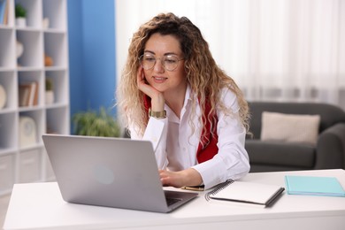Photo of Smiling woman working with laptop at desk in home office