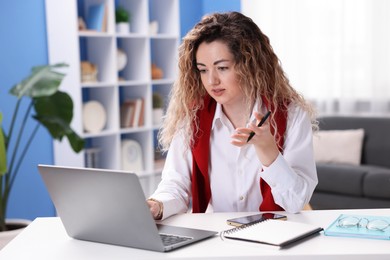 Photo of Woman having videochat by laptop at desk in home office