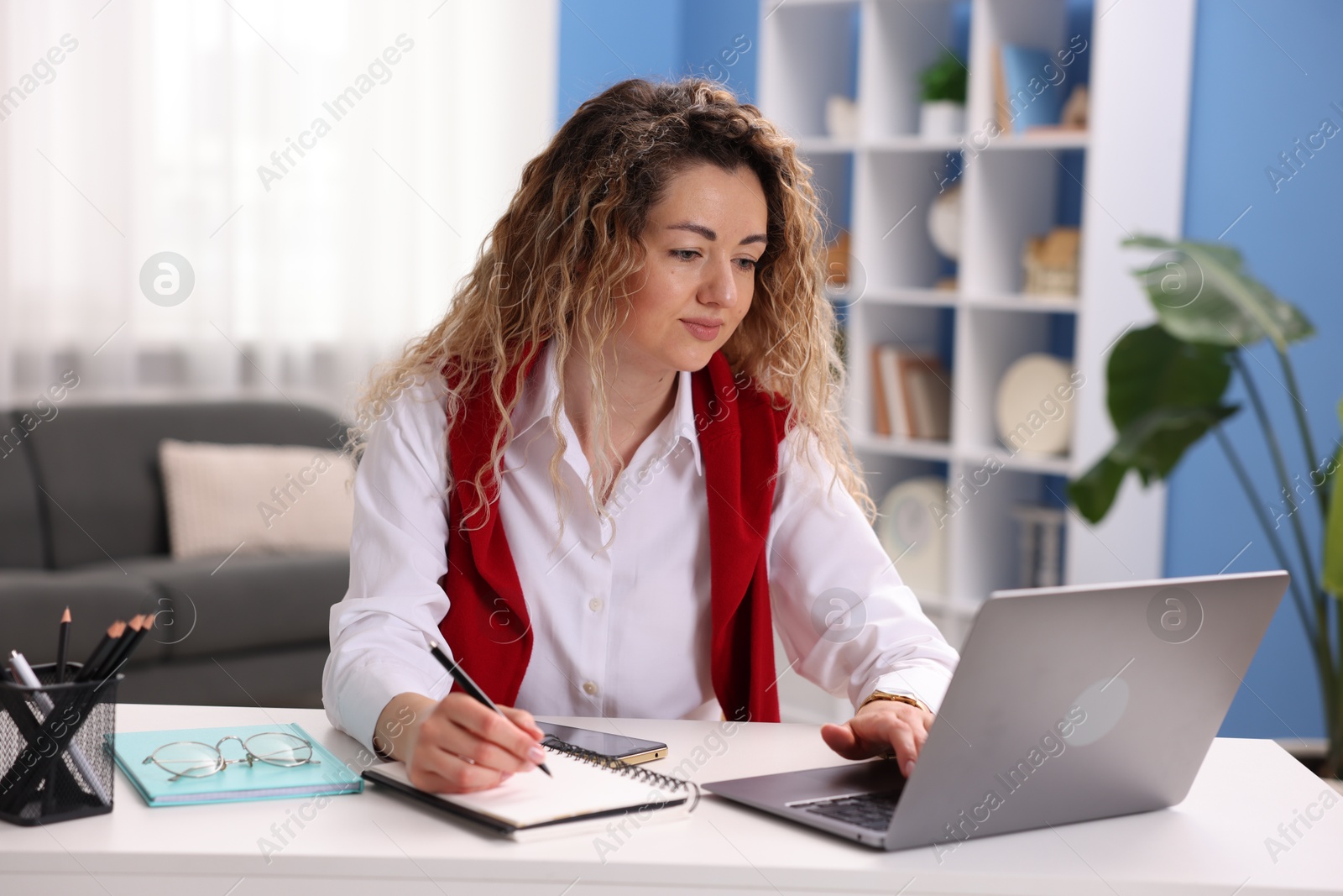 Woman working with laptop at desk in home office Photo of Woman working with laptop at desk in home office