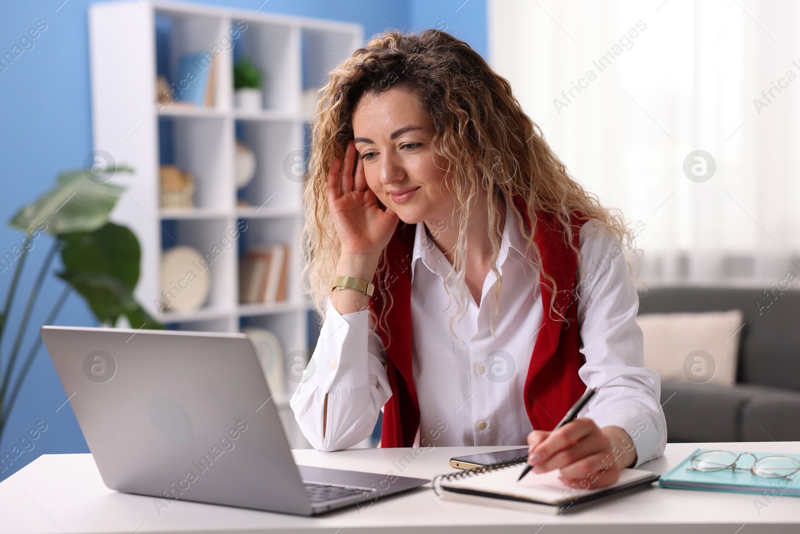 Woman working with laptop at desk in home office Photo of Woman working with laptop at desk in home office
