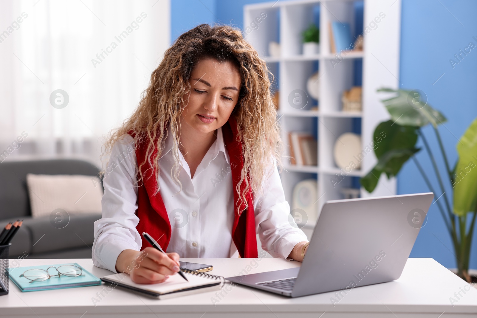 Woman working with laptop at desk in home office Photo of Woman working with laptop at desk in home office
