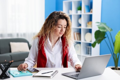 Photo of Woman working with laptop at desk in home office