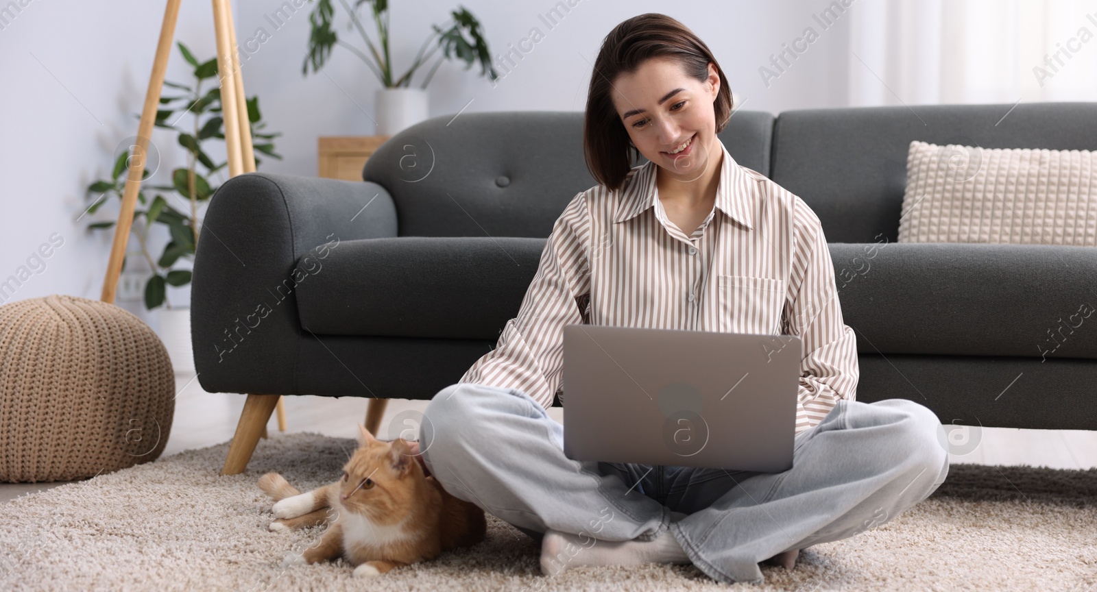 Smiling woman working with laptop and cat on floor in home office Photo of Smiling woman working with laptop and cat on floor in home office