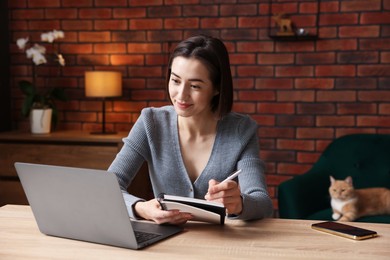 Photo of Woman having videochat by laptop at desk in home office