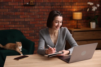 Photo of Smiling woman having videochat by laptop at desk in home office