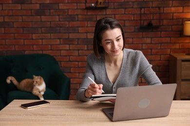 Photo of Woman having videochat by laptop at desk in home office