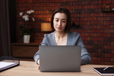 Photo of Woman working with laptop at desk in home office