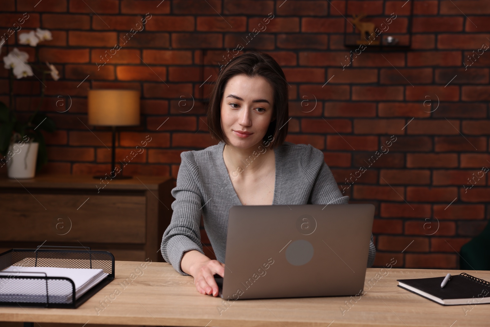 Woman working with laptop at desk in home office Photo of Woman working with laptop at desk in home office