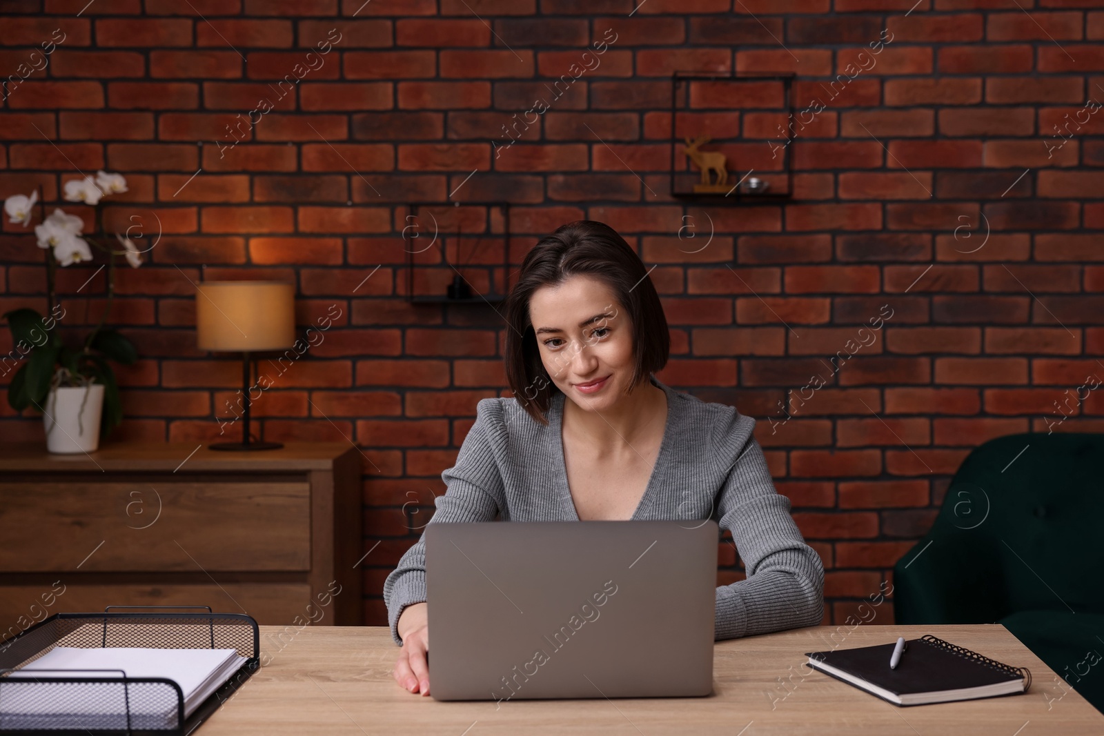 Woman working with laptop at desk in home office Photo of Woman working with laptop at desk in home office