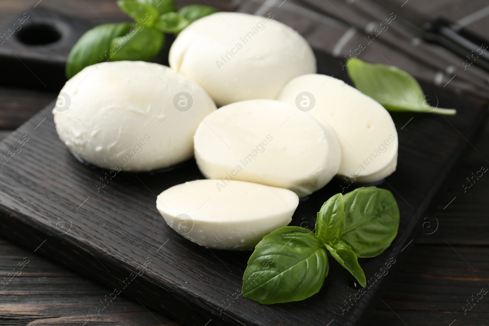 Pieces of delicious mozzarella cheese and basil in bowl on wooden table, closeup Photo of Pieces of delicious mozzarella cheese and basil in bowl on wooden table, closeup