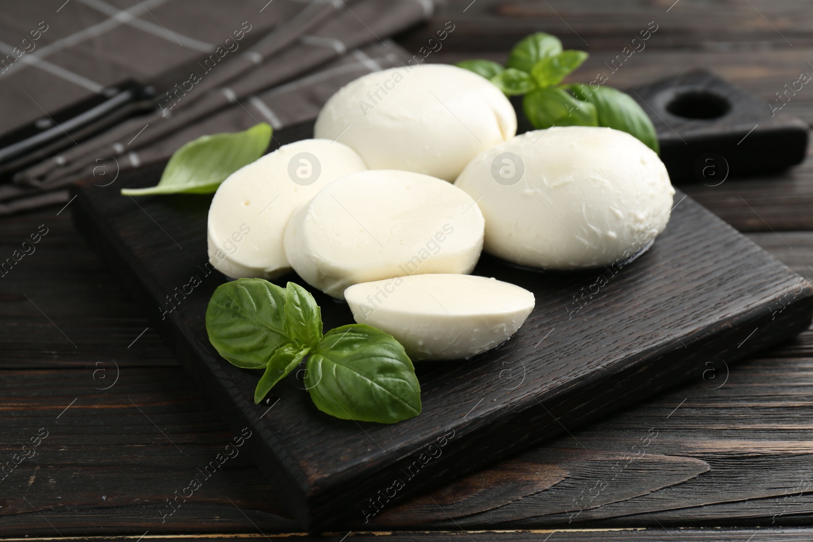 Pieces of delicious mozzarella cheese and basil in bowl on wooden table, closeup Photo of Pieces of delicious mozzarella cheese and basil in bowl on wooden table, closeup