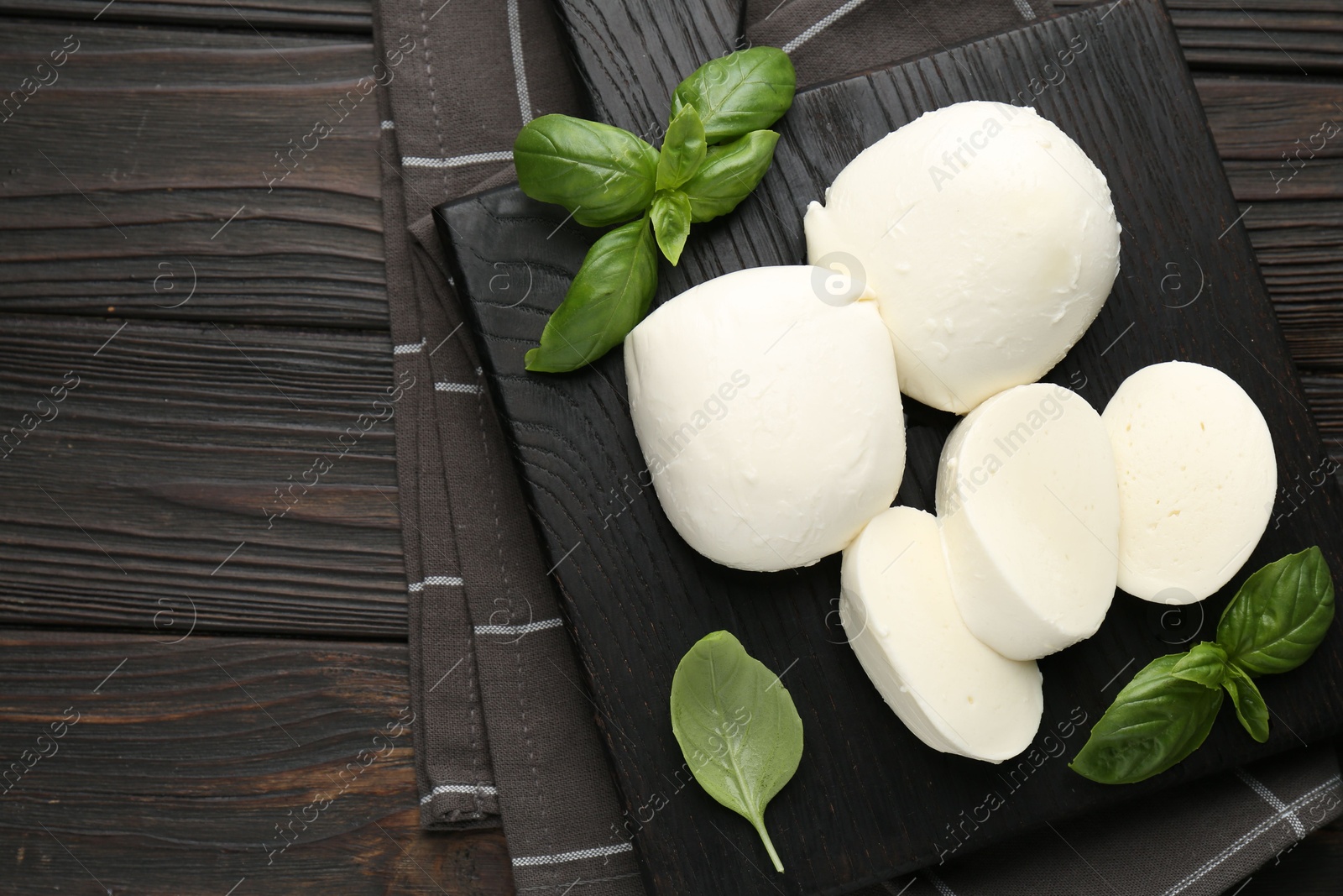 Pieces of delicious mozzarella cheese and basil on wooden table, top view. Space for text Photo of Pieces of delicious mozzarella cheese and basil on wooden table, top view. Space for text