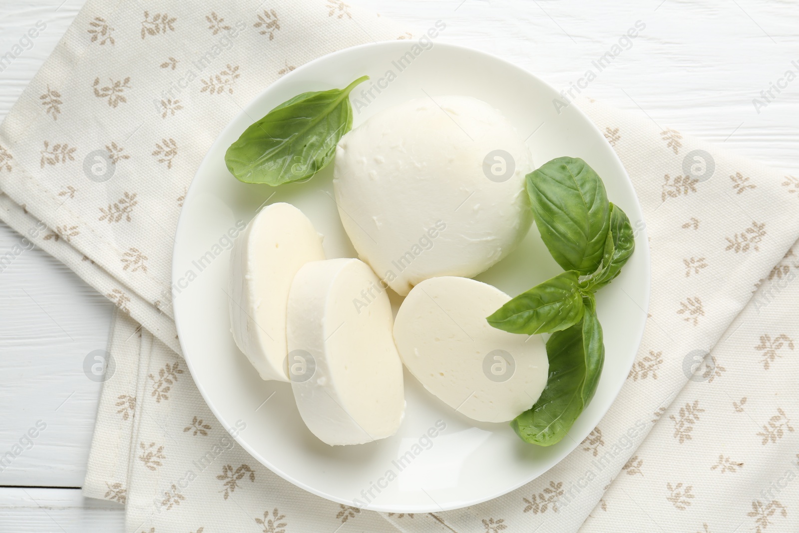 Pieces of delicious mozzarella cheese and basil on white wooden table, top view Photo of Pieces of delicious mozzarella cheese and basil on white wooden table, top view