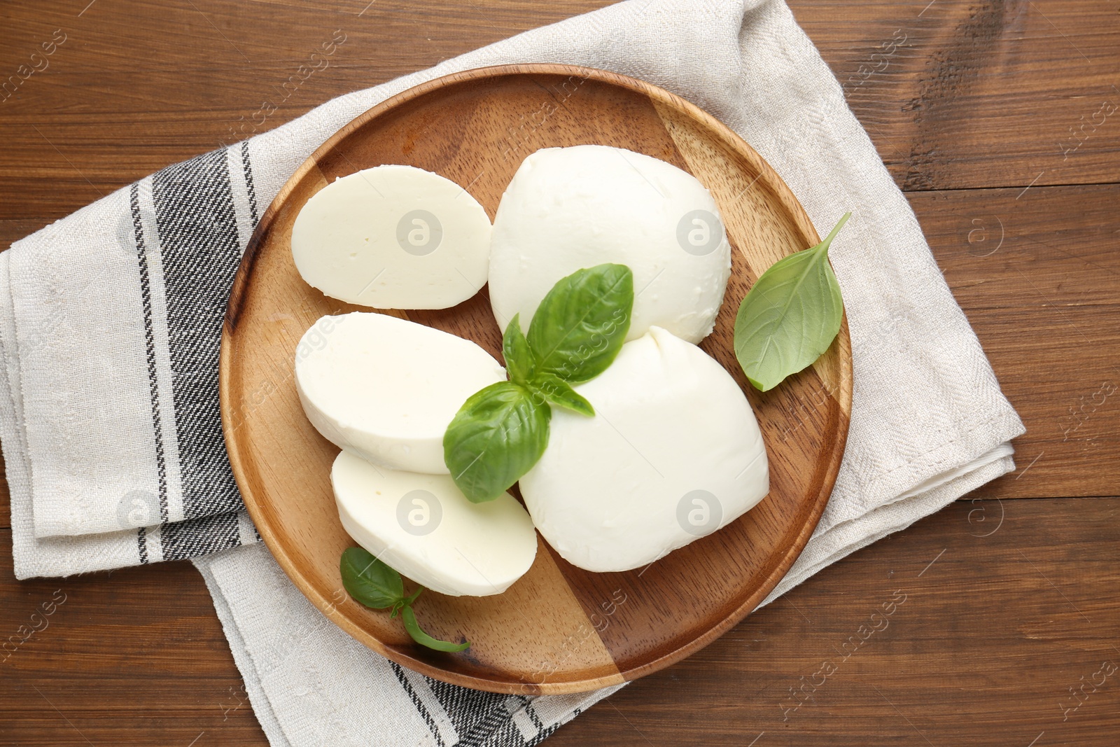 Pieces of delicious mozzarella cheese and basil leaves on wooden table, top view Photo of Pieces of delicious mozzarella cheese and basil leaves on wooden table, top view