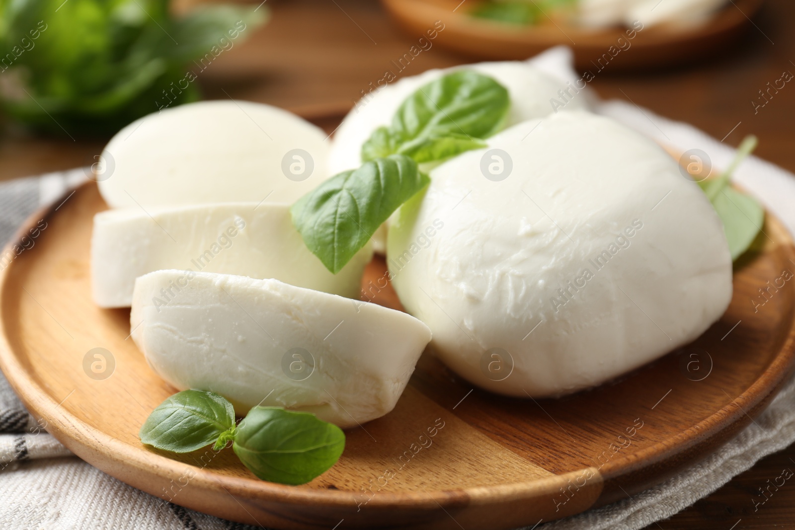 Pieces of delicious mozzarella cheese and basil leaves on wooden table, closeup Photo of Pieces of delicious mozzarella cheese and basil leaves on wooden table, closeup