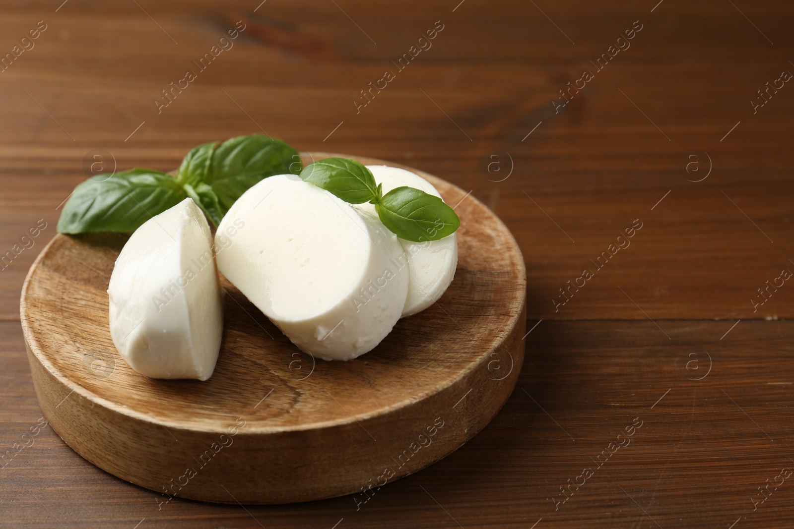 Pieces of delicious mozzarella cheese and basil leaves on wooden table, closeup. Space for text Photo of Pieces of delicious mozzarella cheese and basil leaves on wooden table, closeup. Space for text