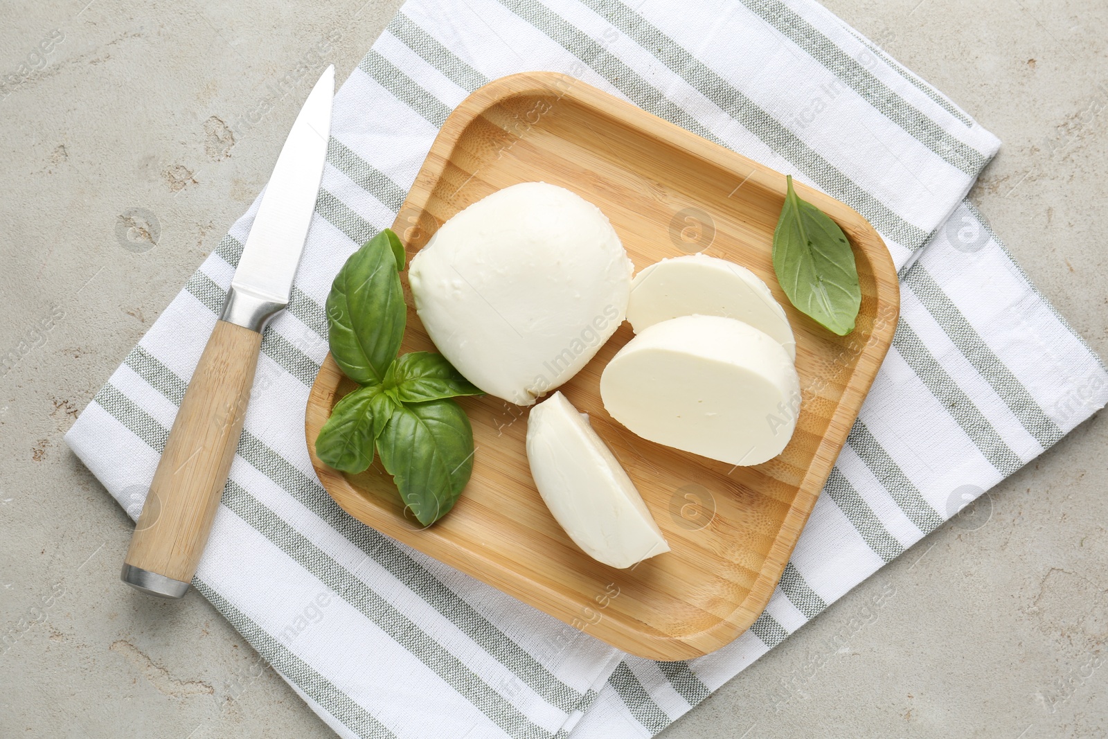 Pieces of delicious mozzarella cheese, basil leaves and knife on grey textured table, top view Photo of Pieces of delicious mozzarella cheese, basil leaves and knife on grey textured table, top view