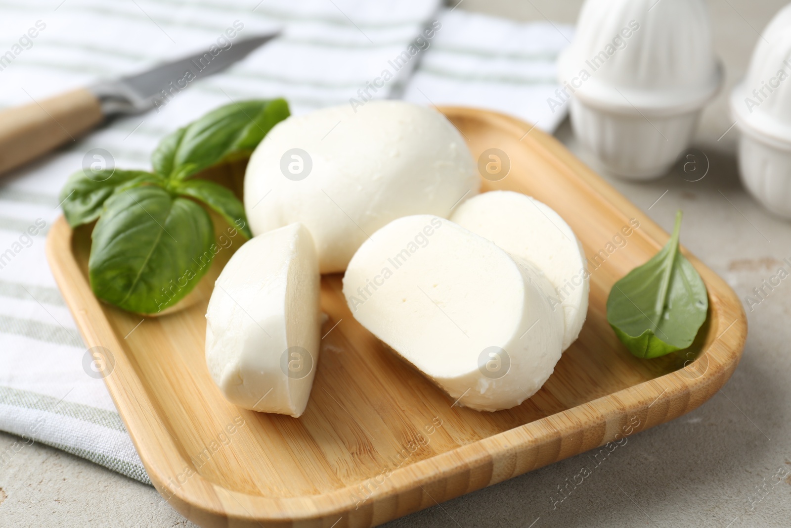 Pieces of delicious mozzarella cheese and basil leaves on grey textured table, closeup Photo of Pieces of delicious mozzarella cheese and basil leaves on grey textured table, closeup
