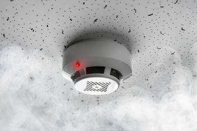 Image of Fire alarm system detector on ceiling triggered by smoke