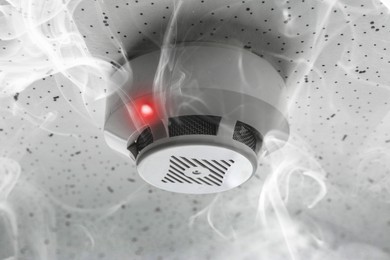 Image of Fire alarm system detector on ceiling triggered by smoke
