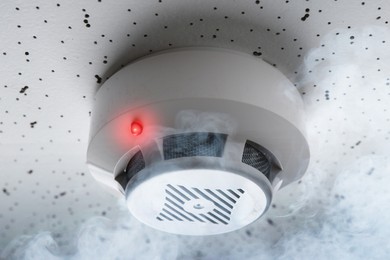 Image of Fire alarm system detector on ceiling triggered by smoke