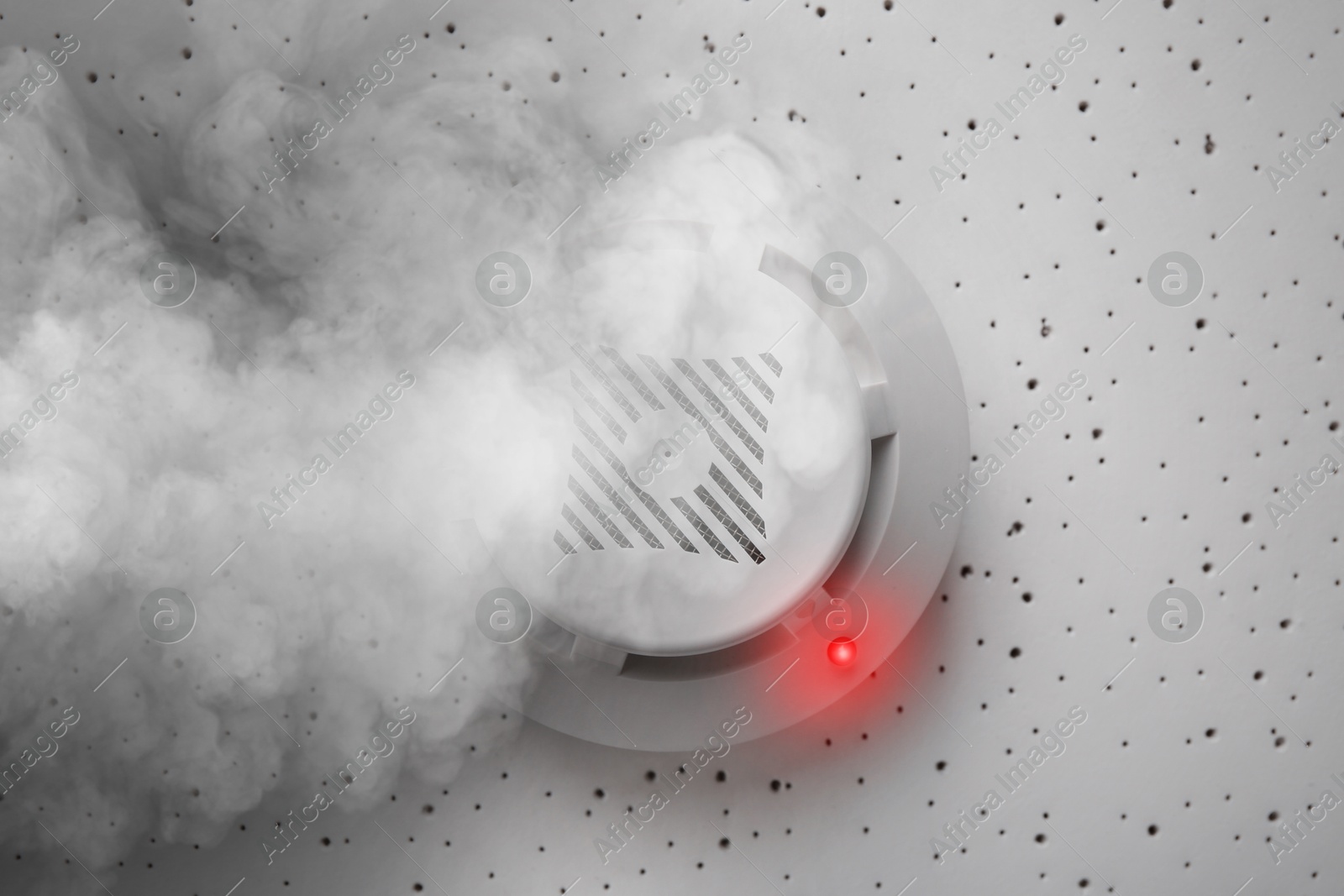 Fire alarm system detector on ceiling triggered by smoke, bottom view Image of Fire alarm system detector on ceiling triggered by smoke, bottom view