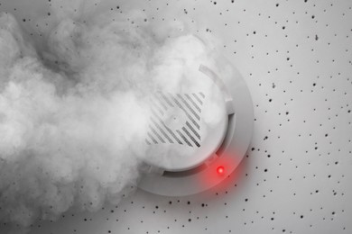 Image of Fire alarm system detector on ceiling triggered by smoke, bottom view