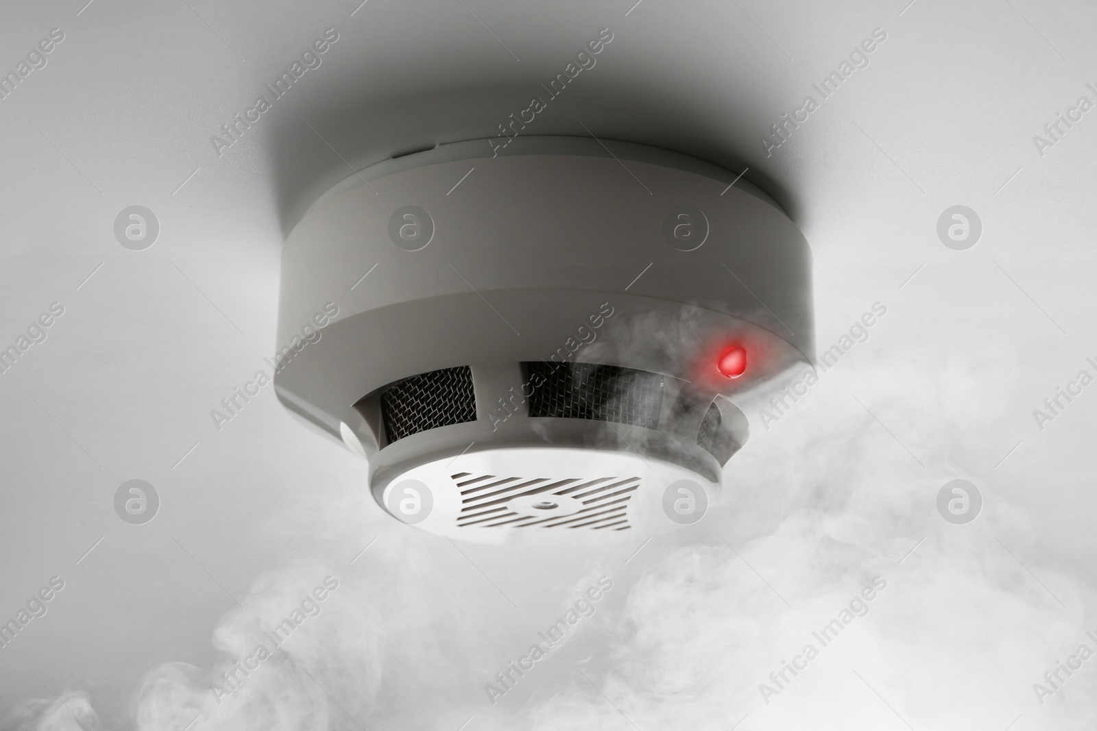 Fire alarm system detector on ceiling triggered by smoke Image of Fire alarm system detector on ceiling triggered by smoke
