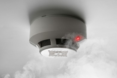 Image of Fire alarm system detector on ceiling triggered by smoke
