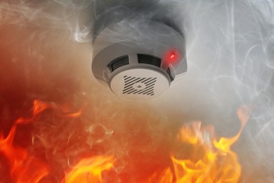Image of Fire alarm system detector on ceiling triggered by smoke and flame