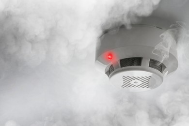 Image of Fire alarm system detector on ceiling triggered by smoke