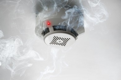 Image of Fire alarm system detector on ceiling triggered by smoke