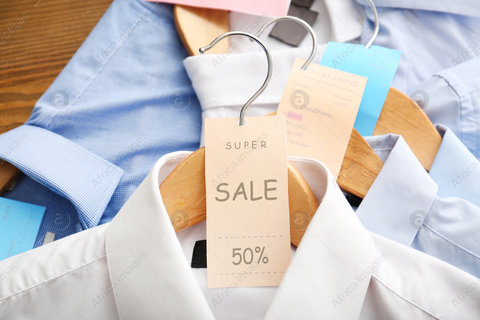 Image of Sale tag on wooden hanger with white shirt, closeup